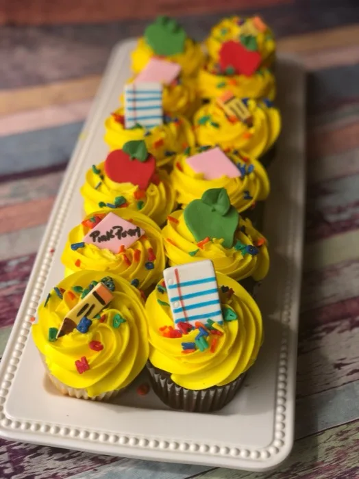 Yellow-frosted back-to-school cupcakes topped with fondant apples, pencils and notebook paper