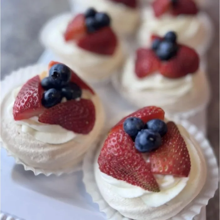 Mini pavlova desserts topped with fresh strawberries and blueberries
